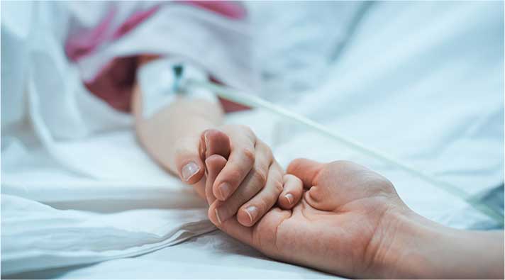 holding a persons hand in hospital bed